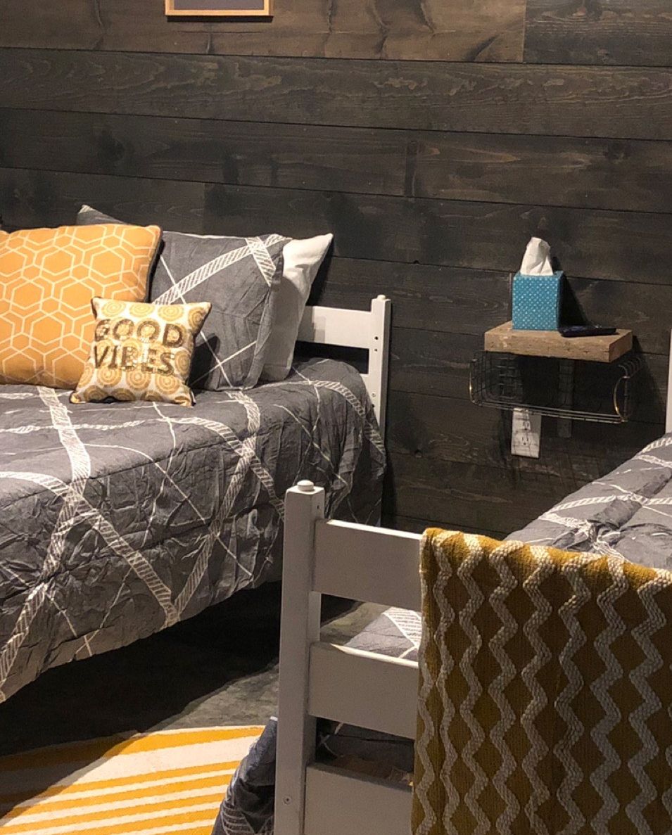 A bedroom with two beds, a nightstand, and a chair.