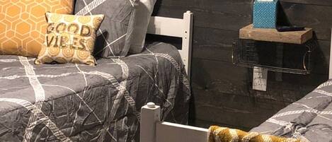 A bedroom with two beds, a nightstand, and a chair.