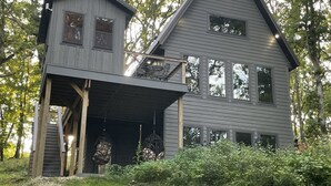 Une maison à deux étages avec une terrasse en bois et un balcon.
