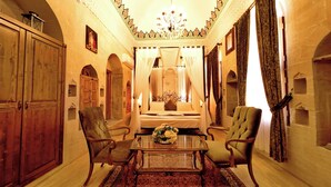 A room with a bed, two armchairs, a wooden table, and a chandelier. - Ulubey Konagi (Mardin)