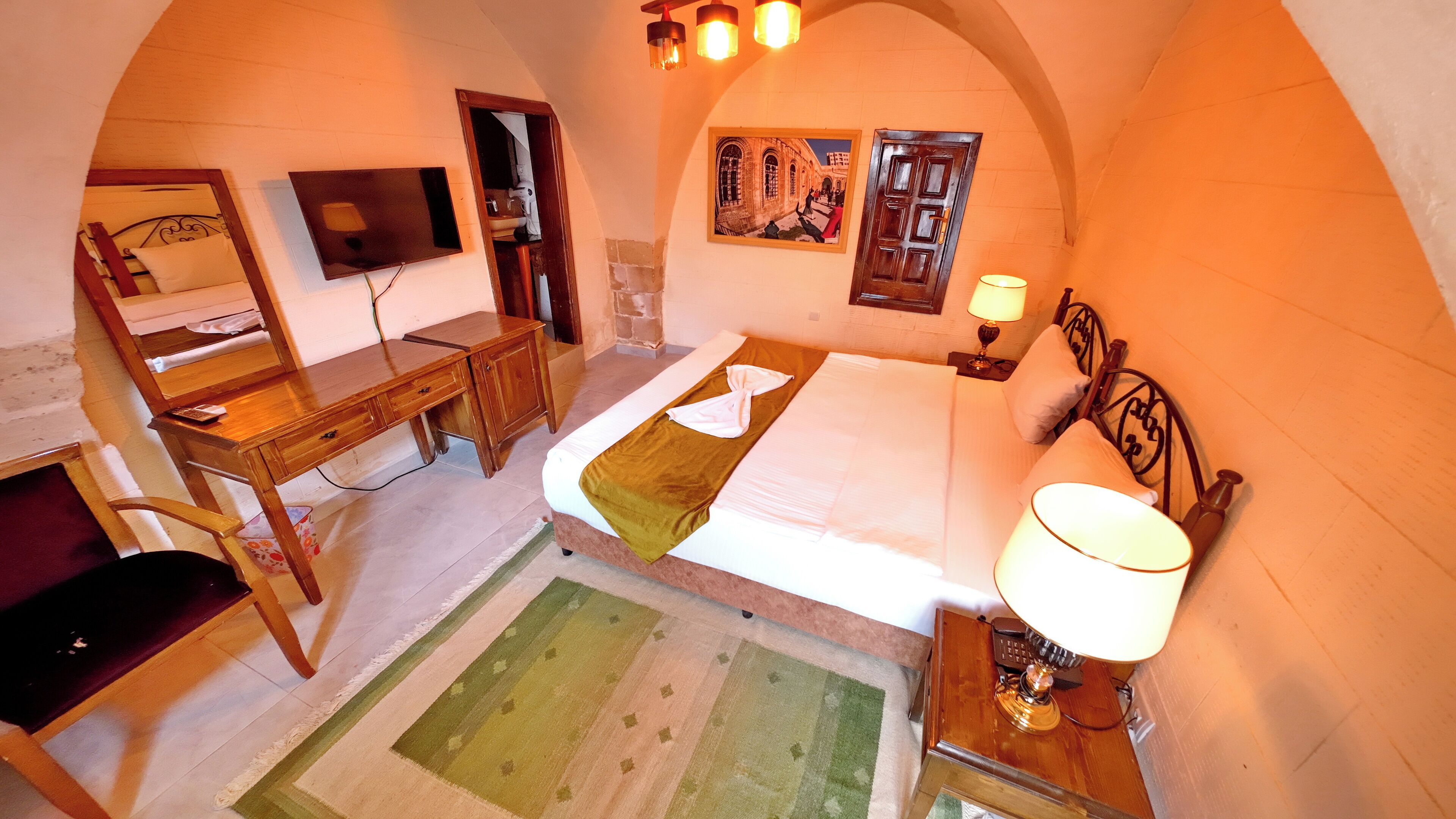 Une chambre à coucher avec un lit, un bureau, une chaise, une lampe et un tableau au mur.
