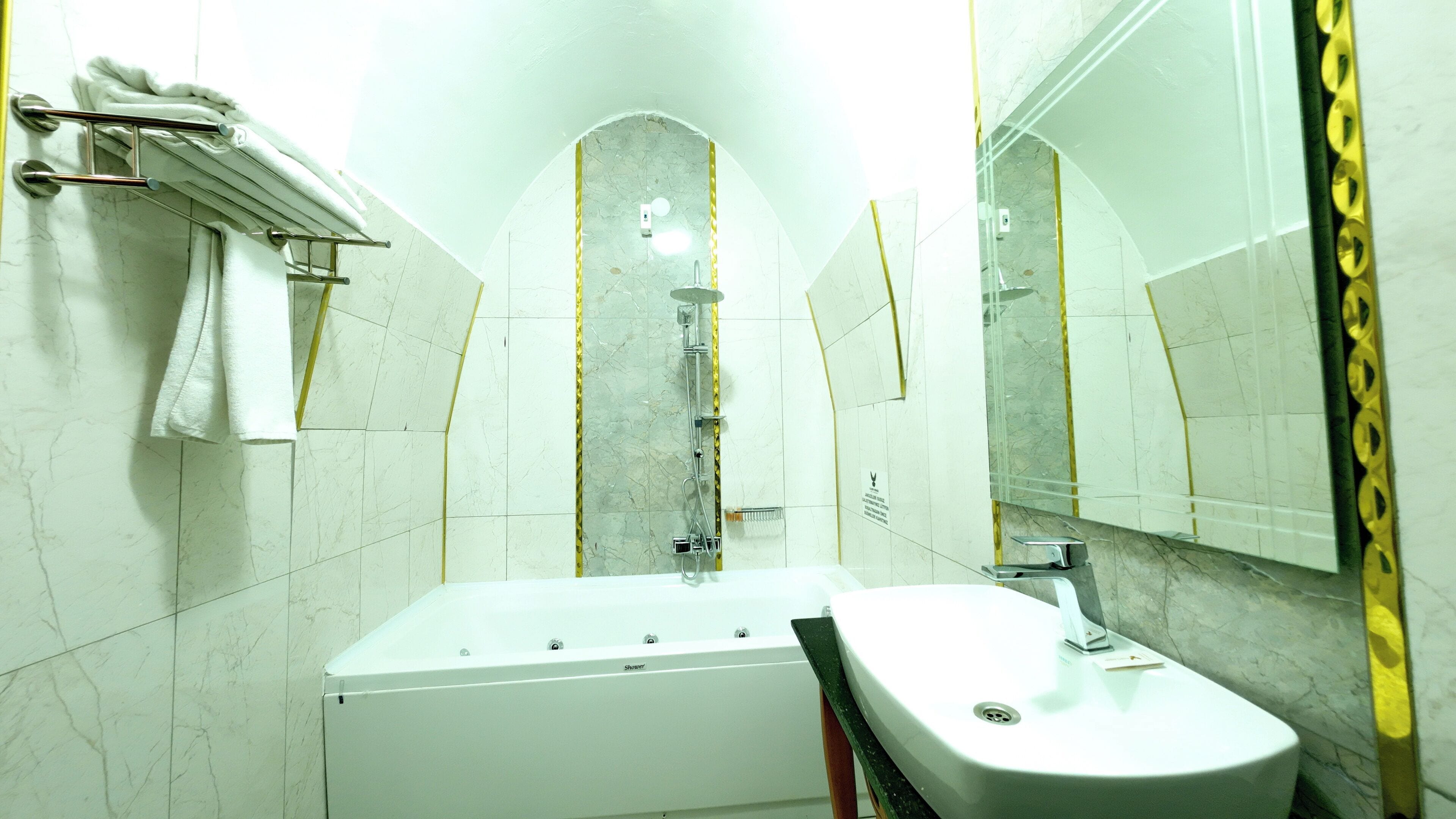 Un baño con bañera, lavamanos, toallero y espejo.