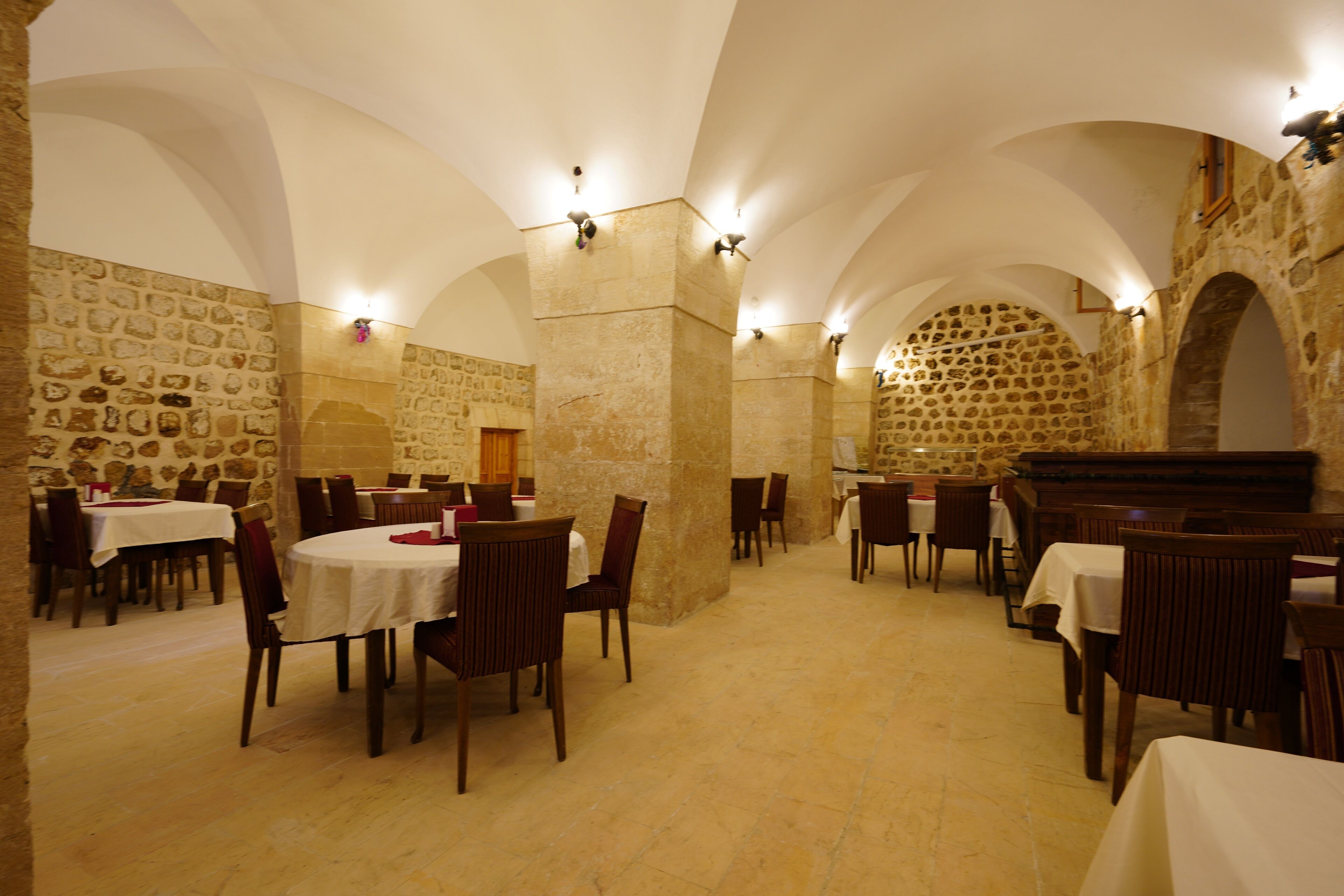 A restaurant with stone walls, arched ceilings, and tables set for dining.