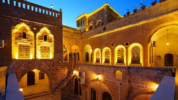 A courtyard with arched walkways and a central staircase. - Ulubey Konagi (Mardin)