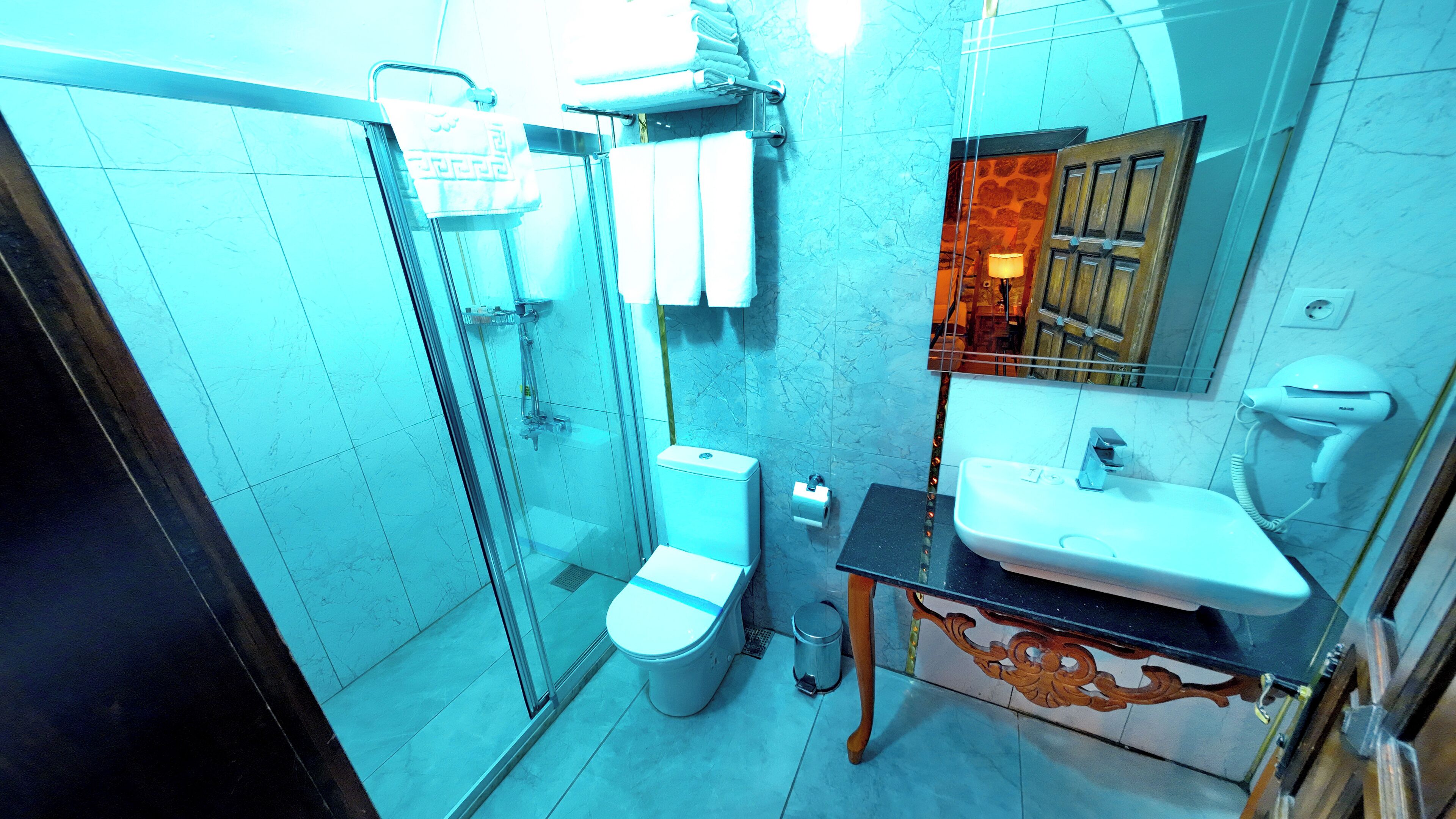 Une salle de bain avec une douche à parois de verre, des toilettes, un lavabo et un miroir.