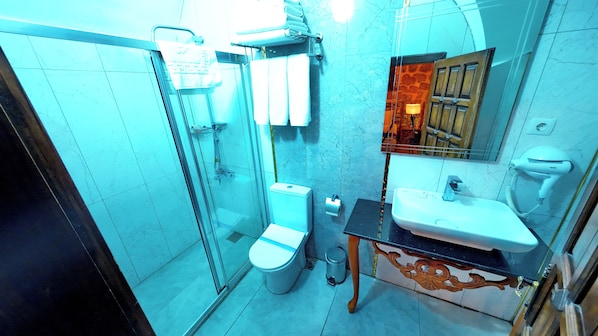 Un baño con ducha de mampara de vidrio, inodoro, lavamanos y espejo.