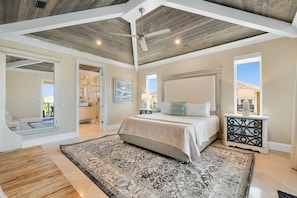 A spacious bedroom with a large bed, a ceiling fan, and a view of the outside.