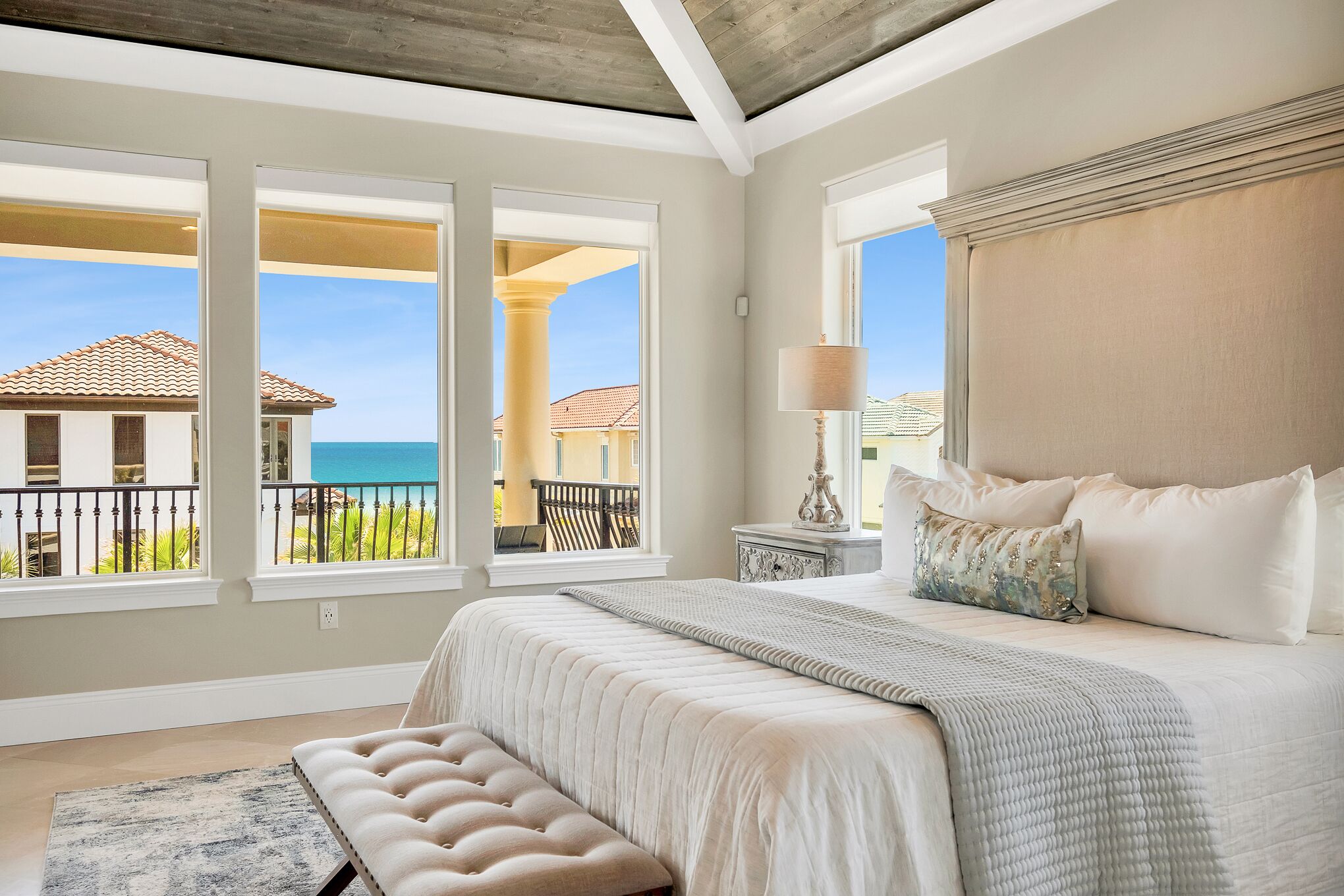 Ein Schlafzimmer mit einem großen Bett, Meerblick und einem Balkon mit Geländer.