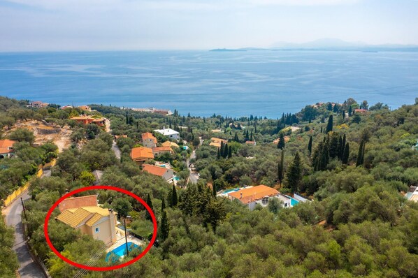 A coastal village with houses surrounded by greenery and a view of the sea.