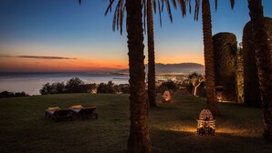 A sunset view with palm trees, a grassy area with lounge chairs, and a decorative lantern. - Cubo's Mountain Bayview Luxury Villa / views / free wifi / gym (Málaga)