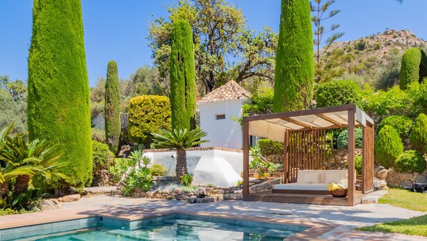 A pool area with a pergola seating area, surrounded by well-maintained greenery and a white building in the background. - Cubo's Mountain Bayview Luxury Villa / views / free wifi / gym (Málaga)