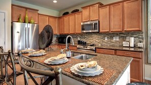 Une cuisine moderne avec des meubles en bois, des appareils électroménagers en acier inoxydable et un plan de travail en granit.