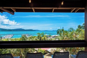 A view from a window overlooking a marina with boats, palm trees, and a clear blue sky. - Beyond The Palms (Airlie Beach)