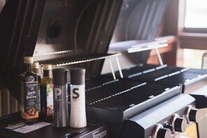 Un barbecue avec des condiments et une bouteille d’huile d’olive.