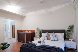 Ein Hotelzimmer mit Bett, Nachttischen, einem Schrank und einer Tür zu einem weiteren Raum.