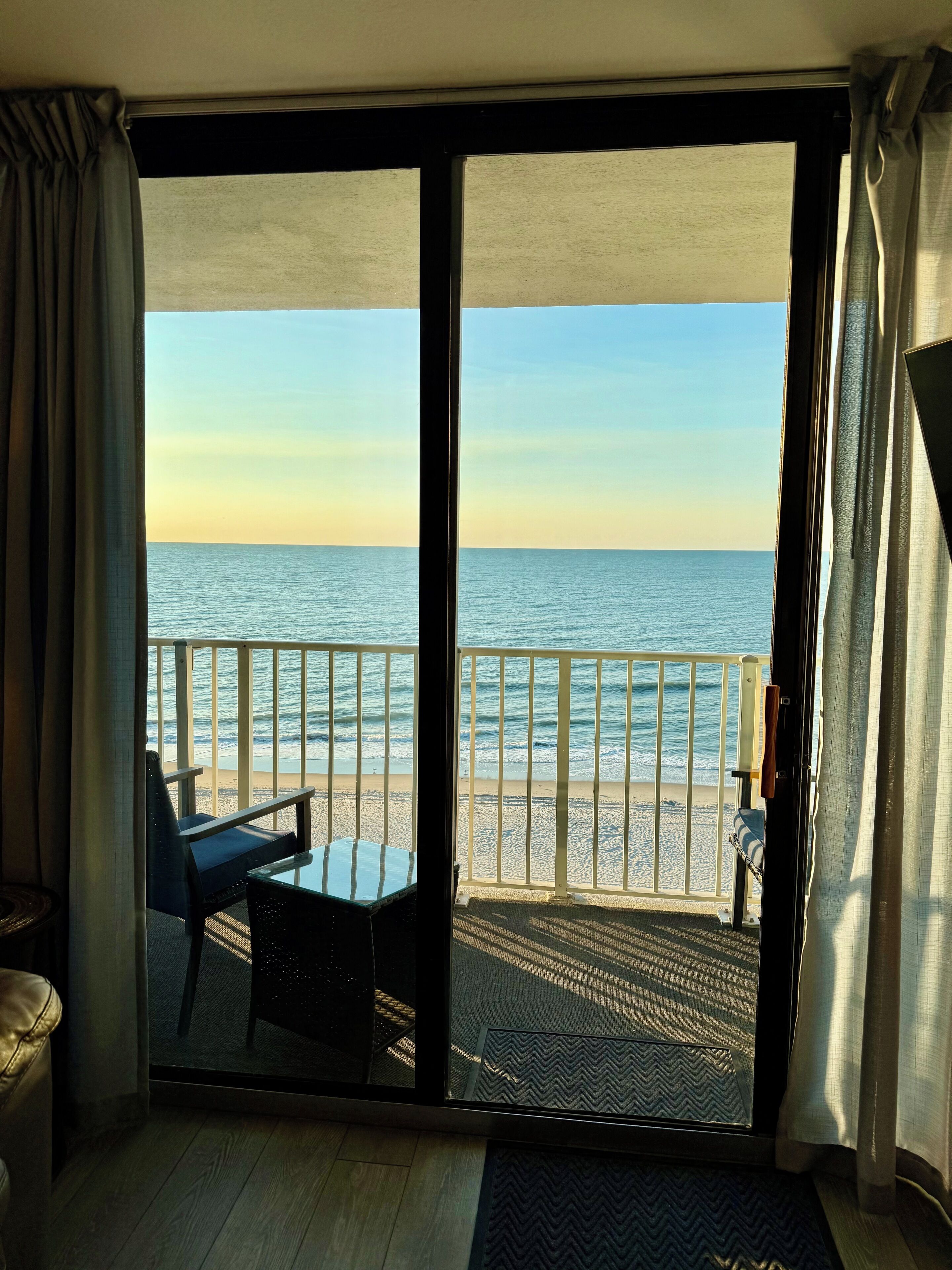 Una habitación con vista a la playa y al océano a través de un amplio ventanal corredero.