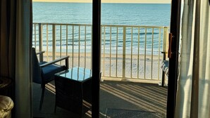 Una habitación con vista a la playa y al océano a través de un amplio ventanal corredero.
