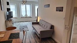 Uma sala de estar moderna com um sofá, uma mesa de jantar e uma televisão.