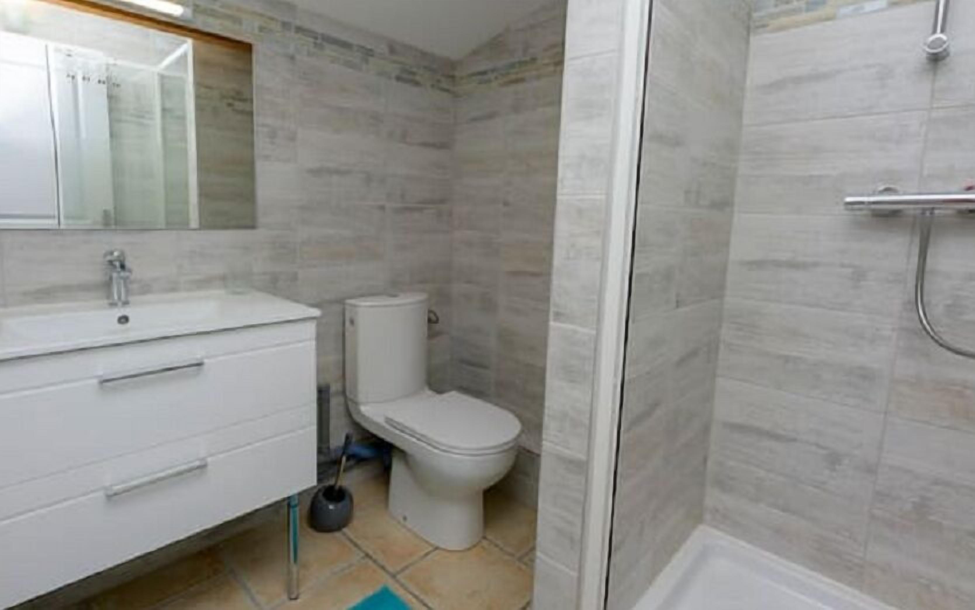A bathroom with a white sink, toilet, and shower.
