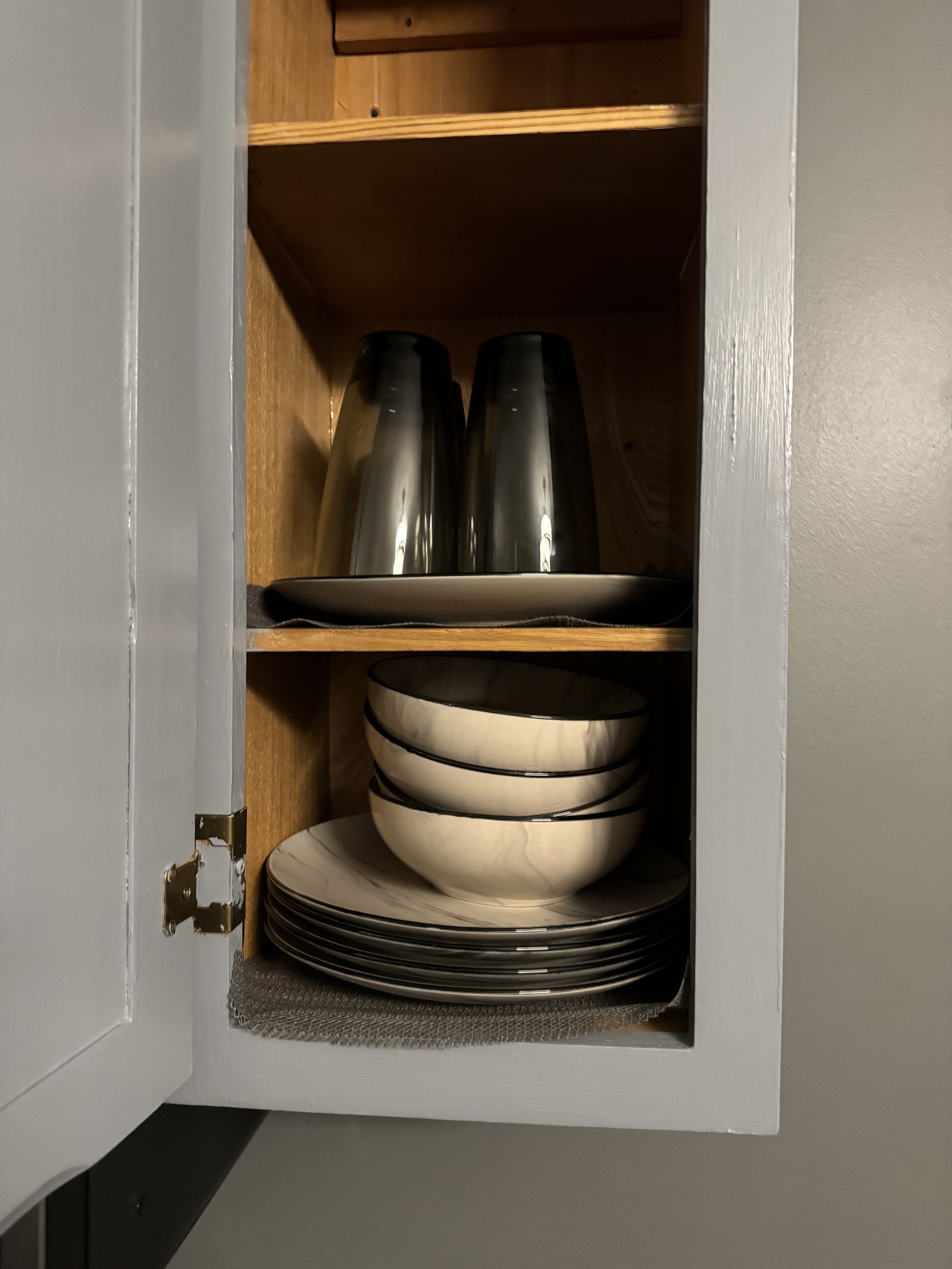 A cabinet with shelves holding black and white dishes.