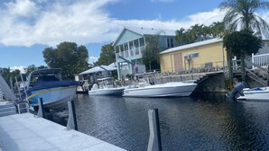 Un puerto deportivo con barcos amarrados, un pequeño puente y un edificio con balcón.