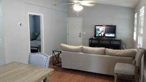A living room with a ceiling fan, a television on a stand, a sofa, a dining table, and a chair. - Tampa two bedroom, two bathroom Lakehouse II (Tampa)