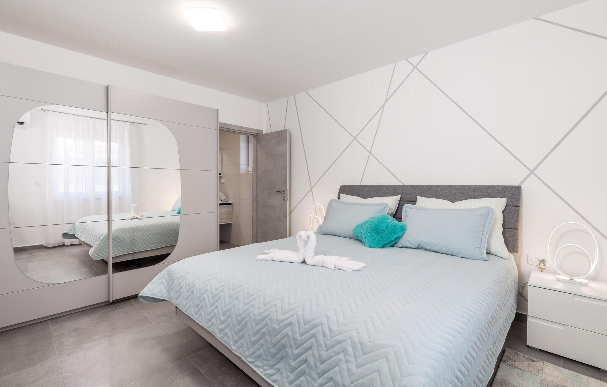 Une chambre à coucher moderne avec un lit, un miroir et une table de chevet.