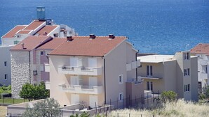 En bostadsbyggnad vid kusten med flera balkonger, en fasad av sten och utsikt över havet.