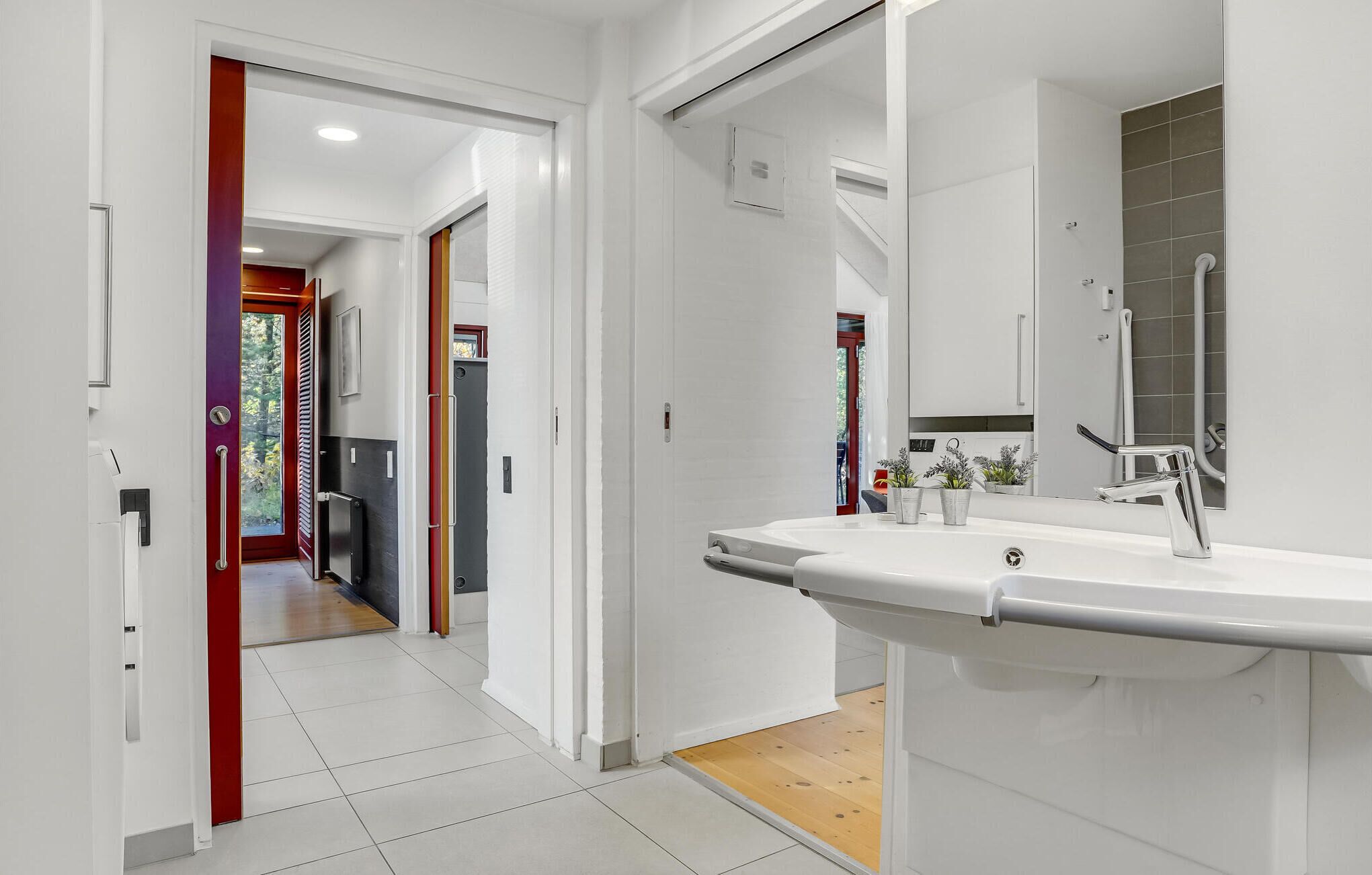 A modern bathroom with a large mirror, white sink, and a shower area.