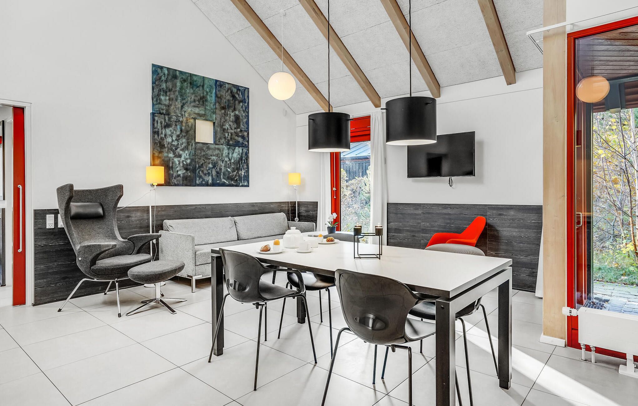 A modern dining area with a white table, black chairs, and a large abstract painting on the wall.