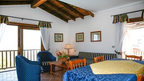 A room with a balcony, a sofa, a dining table, and a chair. - Cozy home in Punta Su Turrione (Punta Su Turrione)