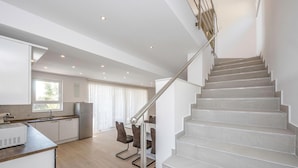 A modern kitchen with a built-in oven, a dining area with a table and chairs, and a staircase with a metal railing. - Awesome home in Banjol (Banjol)