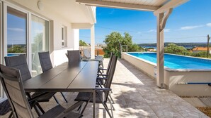 A covered outdoor area with a pool, a dining table with chairs, and a view of the sea. - Awesome home in Banjol (Banjol)