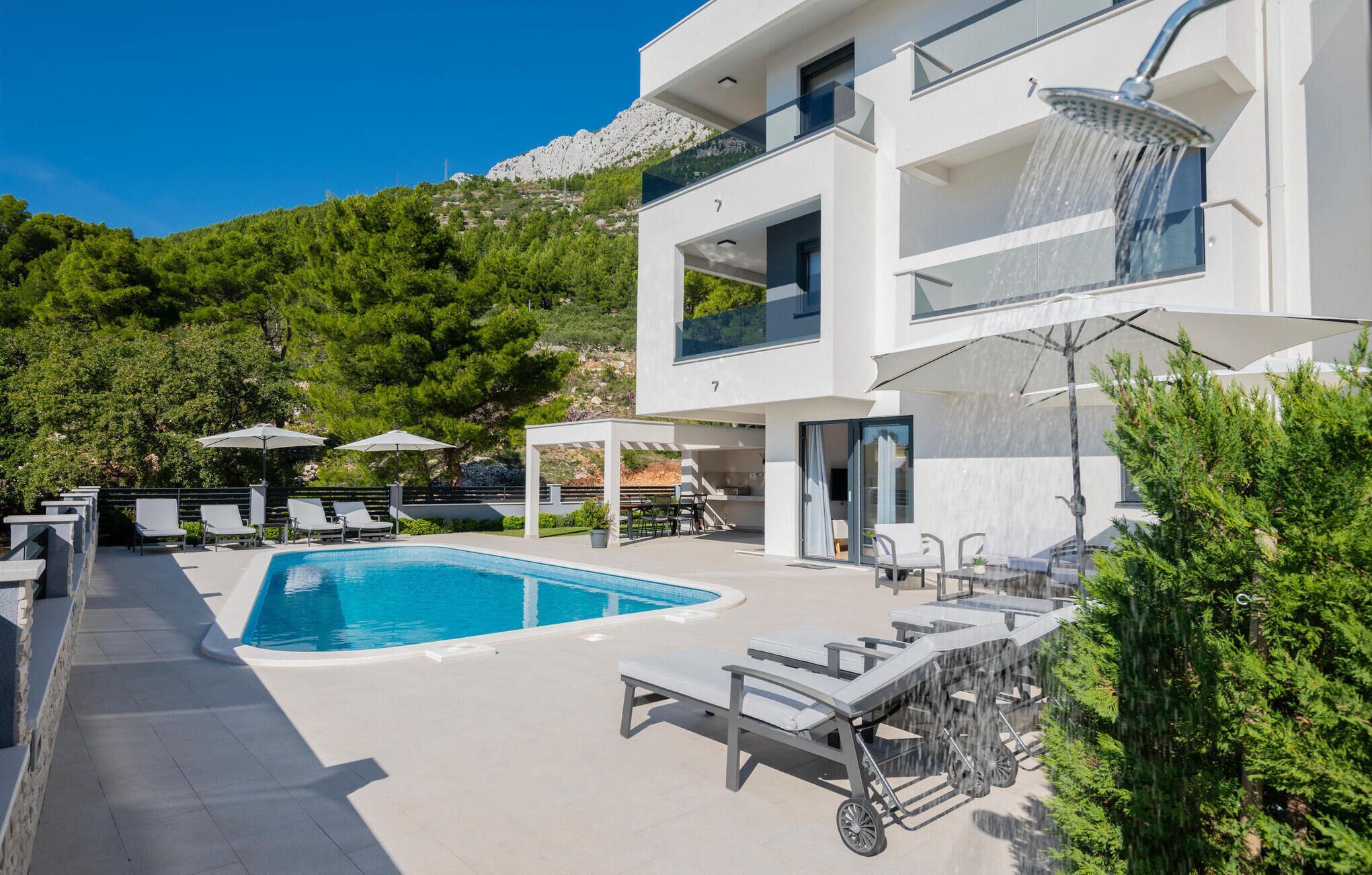Ein modernes, zweistöckiges Gebäude mit Pool, Sitzgelegenheiten im Freien und Bergblick.