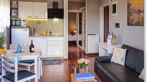 Un espacio habitable compacto con kitchenette, comedor y sala de estar con sofá y mesa de centro.
