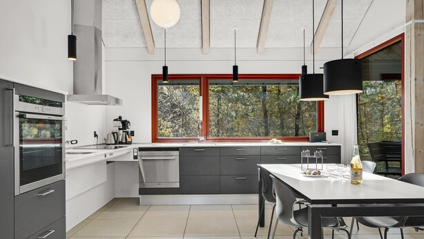 A modern kitchen with a large window, stainless steel appliances, and a dining area with a table and chairs. - Lovely home in Grenaa with kitchen (Grenaa)