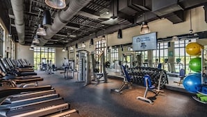 Une salle de sport spacieuse équipée de tapis de course, d’appareils de musculation et de ballons d’exercice.