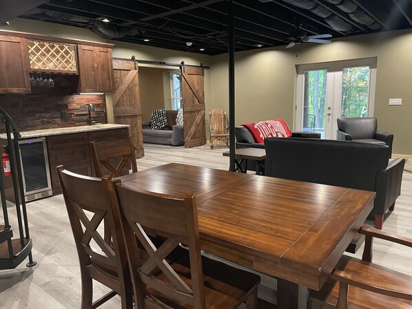 A modern kitchen with wooden cabinets, a built-in wine rack, and a dining area with a wooden table and chairs. - Unique Cavalier Log Cabin nestled in the forest, 15 mins to Hocking Hills (Logan)