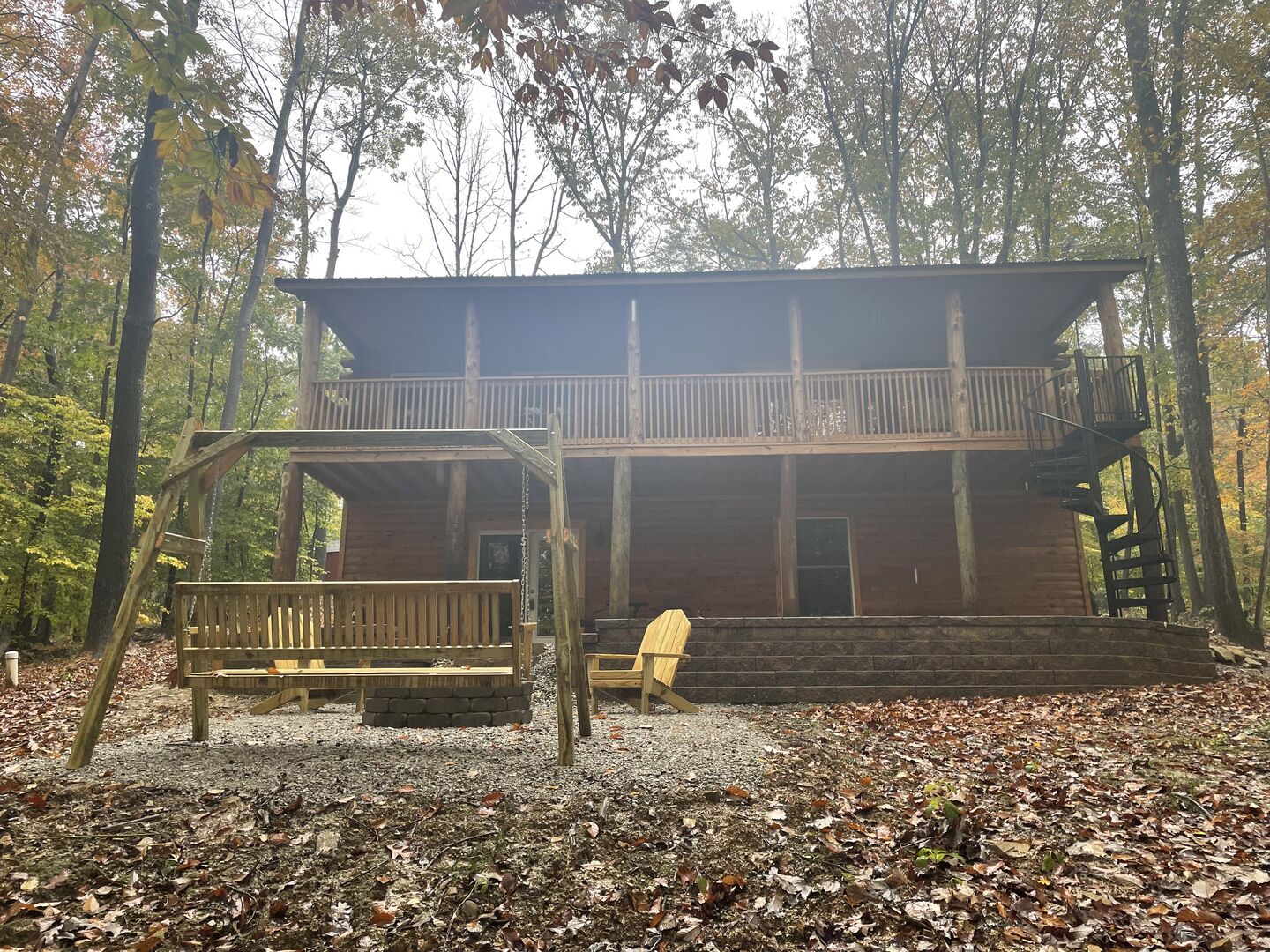 A cabin with a balcony, a staircase, and a bench.