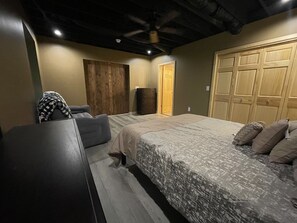 A bedroom with a bed, a dresser, a wardrobe, and a door. - Unique Cavalier Log Cabin nestled in the forest, 15 mins to Hocking Hills (Logan)