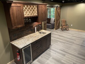 Una cocina con gabinetes de madera oscura, encimera de granito y una vinera empotrada.