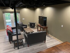 A living room with a fireplace, a TV, and a sofa. - Unique Cavalier Log Cabin nestled in the forest, 15 mins to Hocking Hills (Logan)