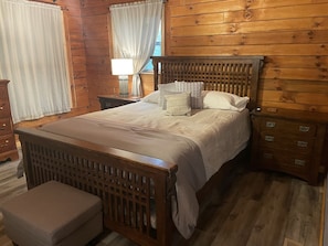 A wooden-paneled room with a bed, a nightstand, a dresser, and a bench. - Unique Cavalier Log Cabin nestled in the forest, 15 mins to Hocking Hills (Logan)