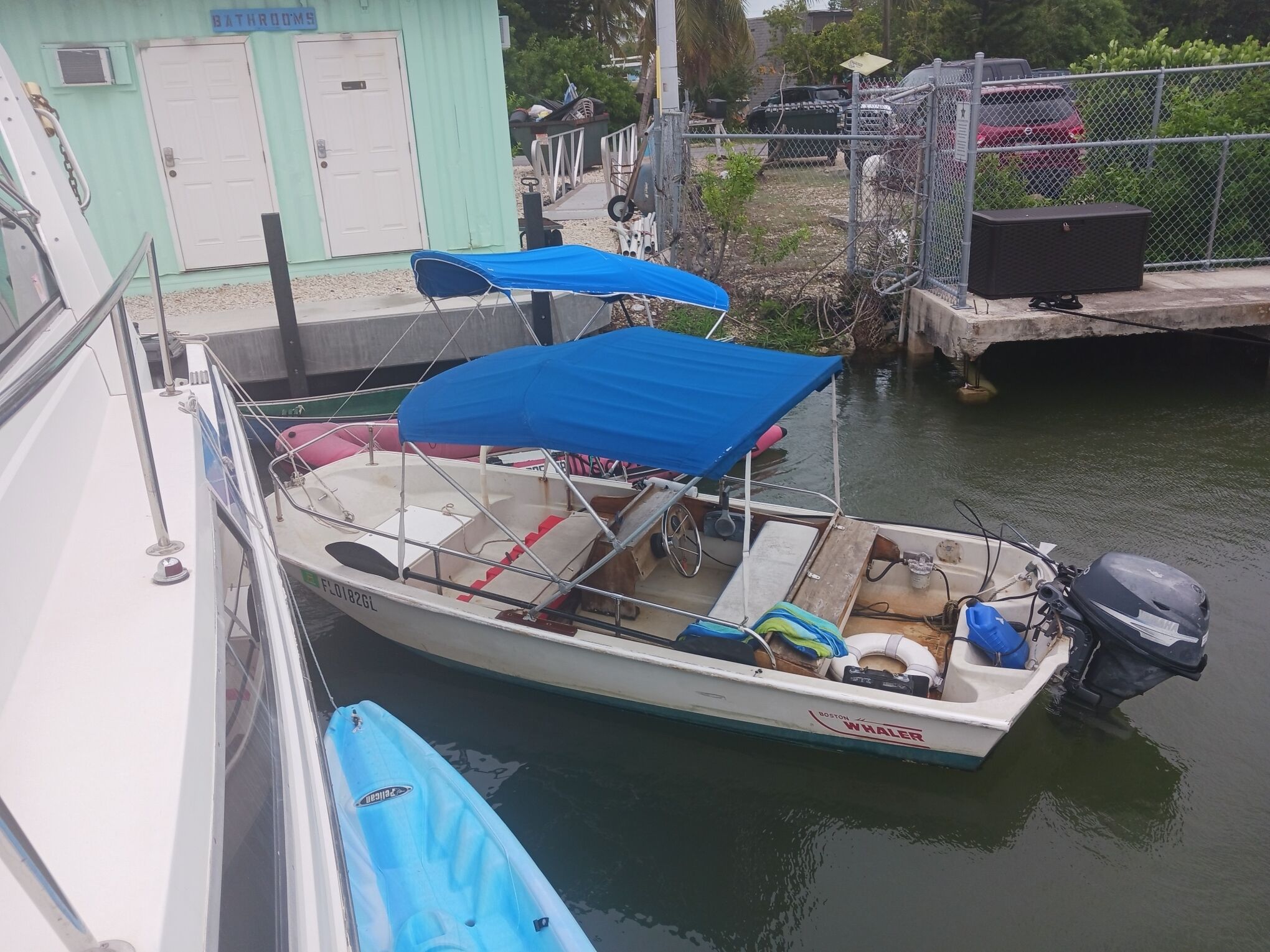 Un petit bateau était amarré dans une marina, sous un auvent bleu, et il portait l’inscription « Boston Whaler ».