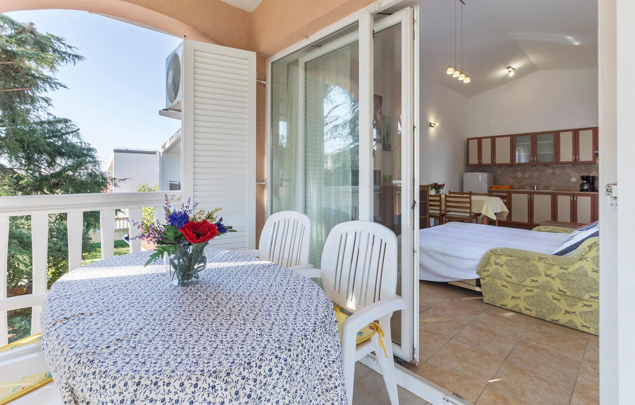 Een balkon met een tafel, stoelen, een bed en een kitchenette.