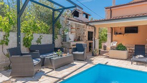A poolside area with wicker furniture, a stone wall, and a tiled roof. - 1 bedroom lovely apartment in Brodarica (Brodarica)