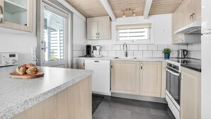 Una cocina moderna con armarios de madera, horno empotrado y cafetera.
