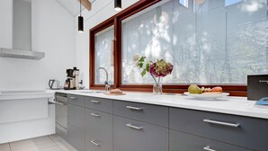 Een moderne keuken met een groot raam, een koffiezetapparaat en een fruitschaal op het aanrecht.