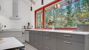 Una cucina moderna con un'ampia finestra, mobili grigi e un piano di lavoro bianco.