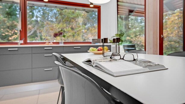 Una cucina moderna con una grande isola, una ciotola di frutta e due bicchieri sul bancone.